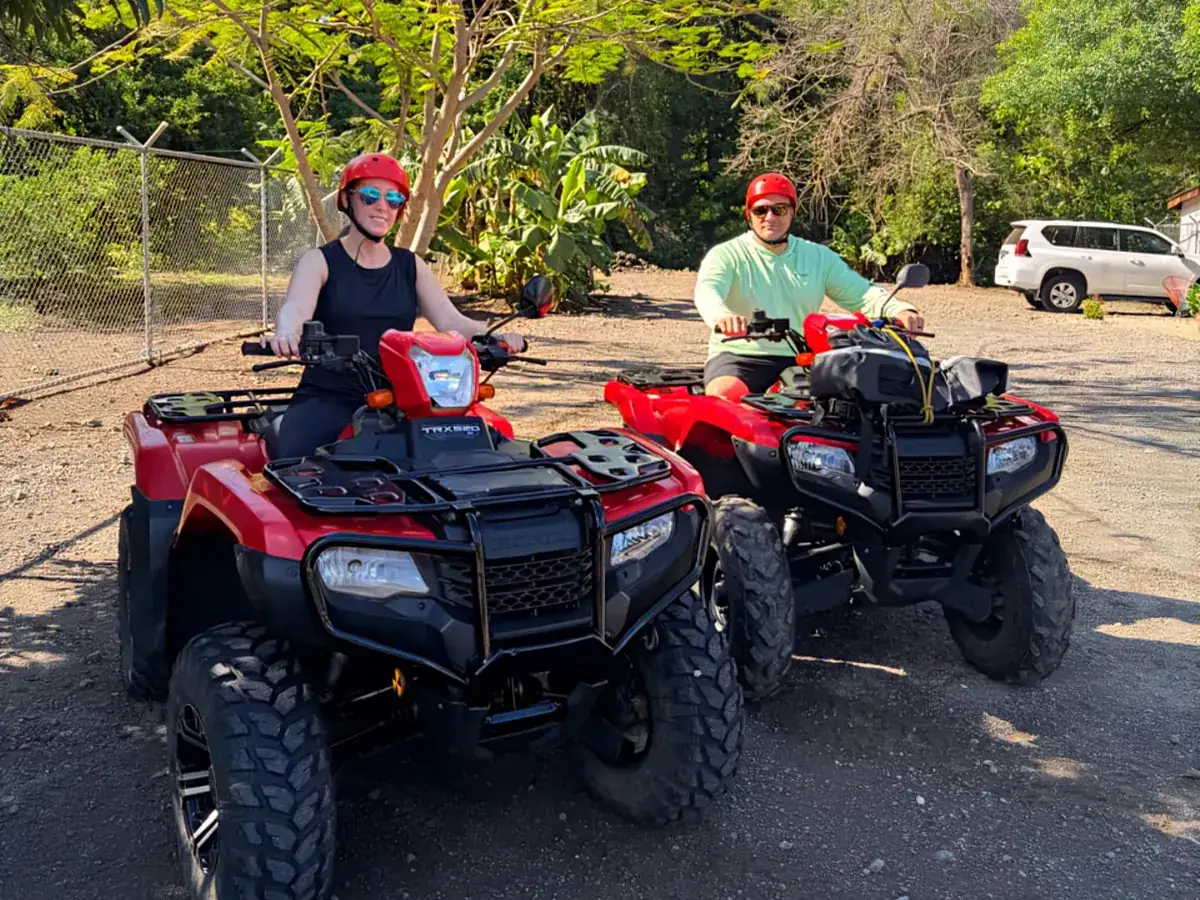 A couple riding red Honda ATVs on a guided tour near Playas del Coco
