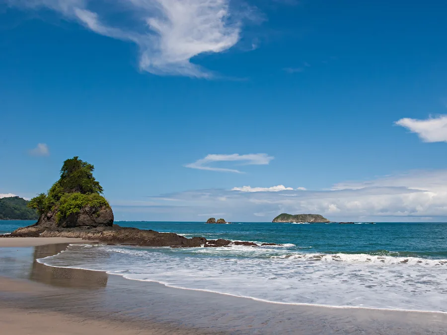 Tropical beach with a forested sea stack and offshore islands on Costa Rica’s Pacific coast
