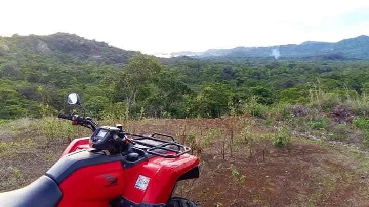 Honda ATV parked at a hilltop viewpoint over the tropical dry forest near Playas del Coco