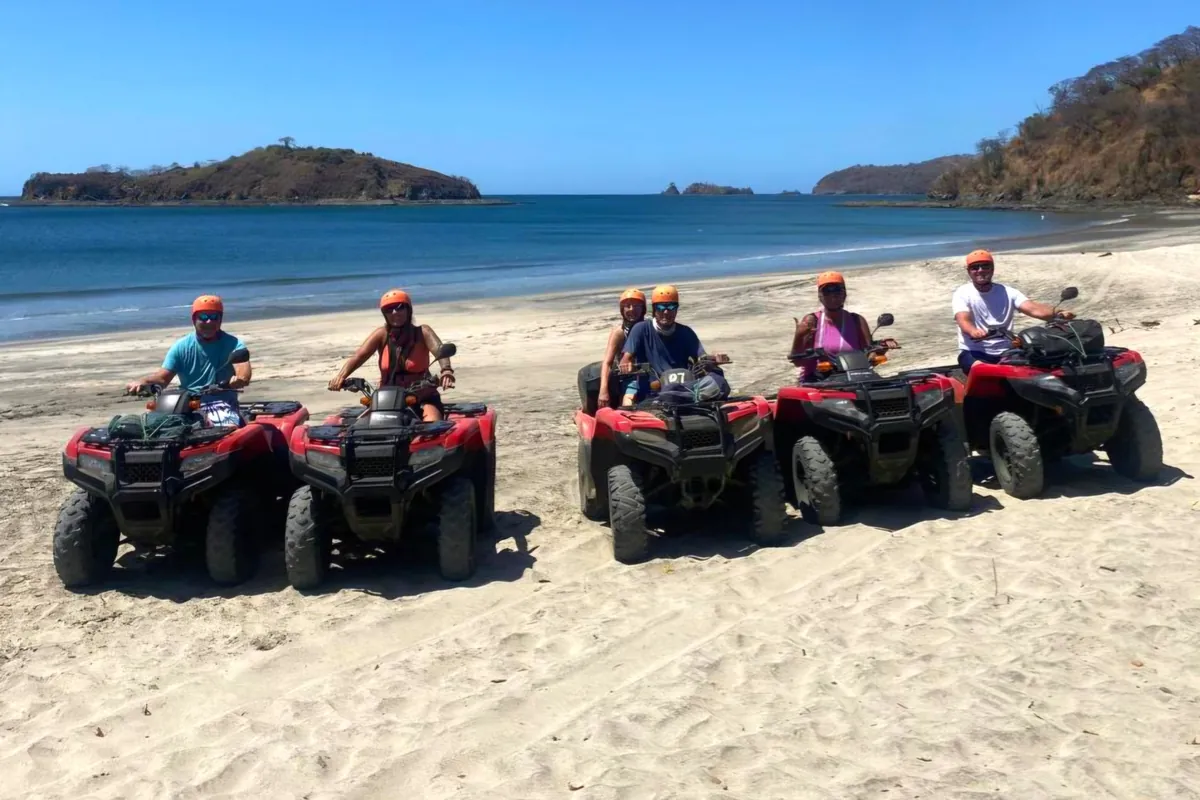 Group on red Honda ATVs on a beach near Playas del Coco with islands offshore