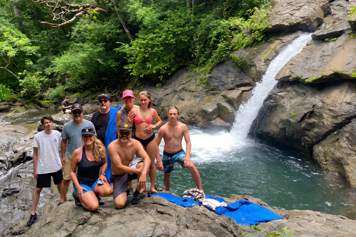 Group of riders posing on the rocks beside a jungle waterfall and swimming hole in Guanacaste