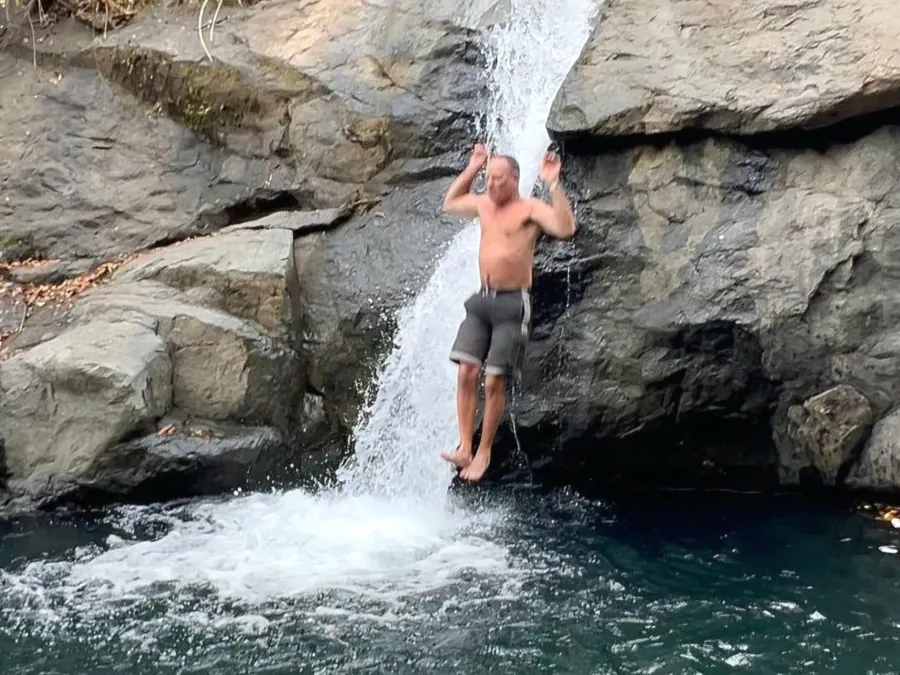 Guest sliding down a waterfall into a natural swimming hole in Guanacaste