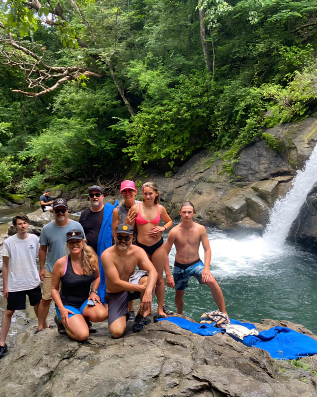 Group of riders posing on the rocks beside a jungle waterfall and swimming hole in Guanacaste