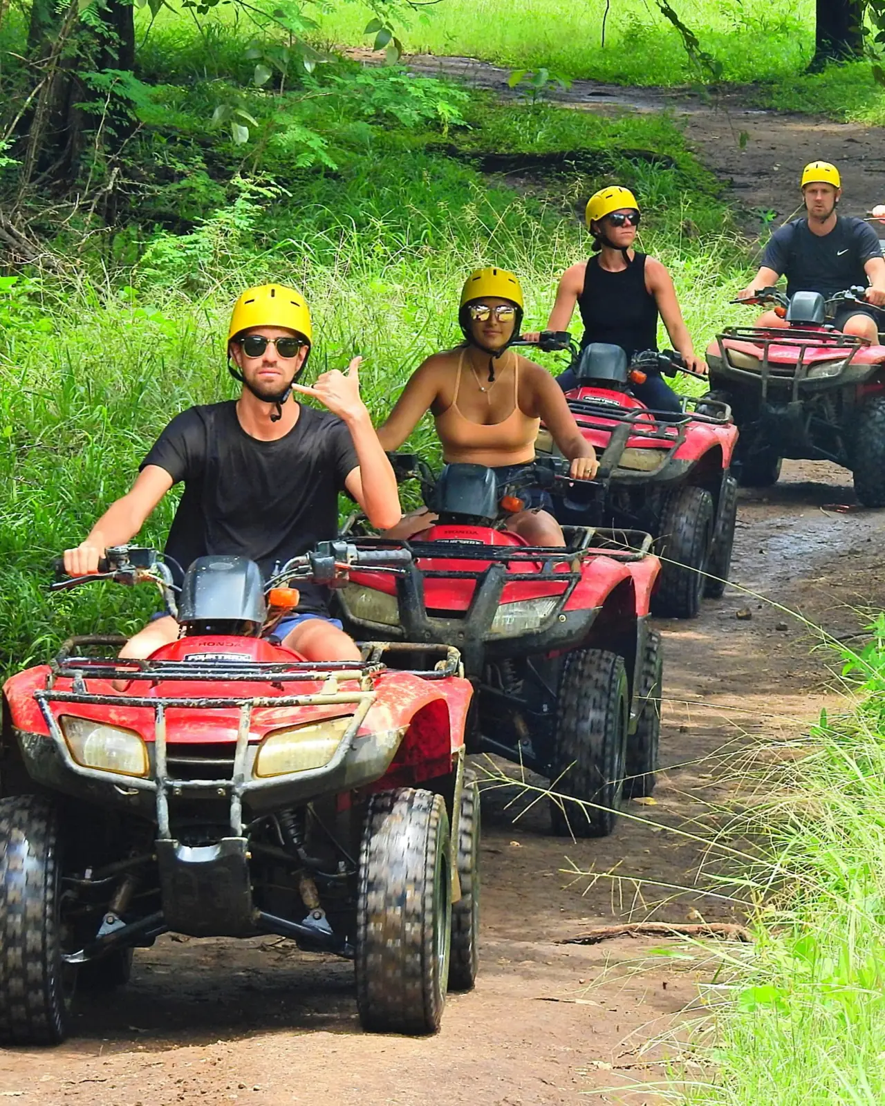 Group riding red Honda ATVs on a forest trail near Playas del Coco