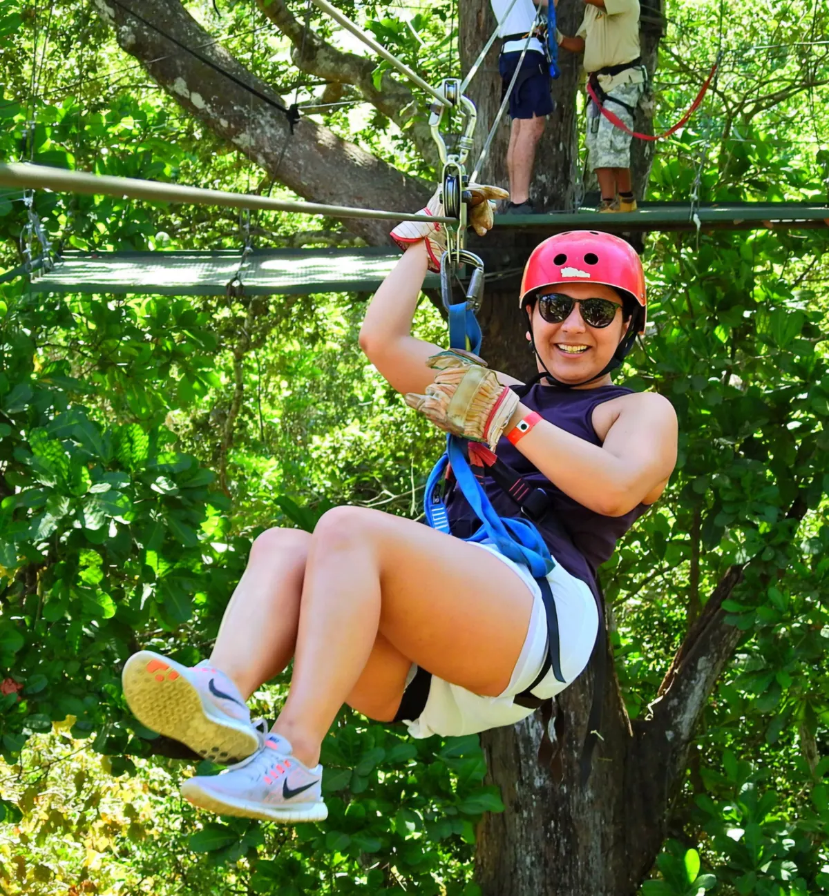 Traveler in a red helmet ziplining between forest platforms on a Congo Trail tour from Playas del Coco