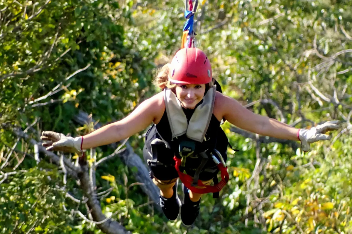Smiling rider flying arms-out on a zipline above the forest canopy at Congo Trail, Guanacaste