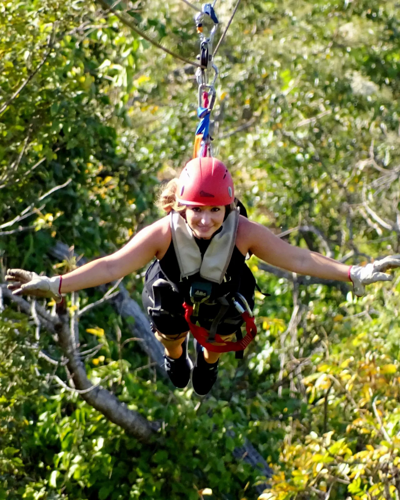 Smiling rider flying arms-out on a zipline above the forest canopy at Congo Trail, Guanacaste