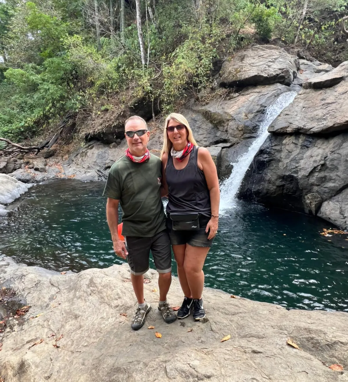 Couple standing on the rocks in front of a waterfall and pool in Guanacaste, Costa Rica
