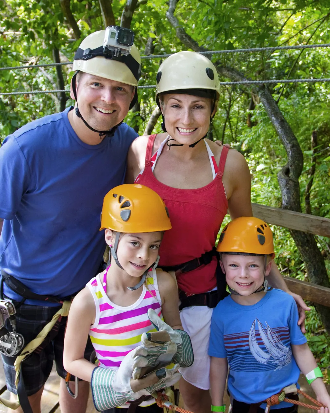 Smiling family in helmets and harnesses on a zipline platform during a day trip from Playas del Coco, Costa Rica