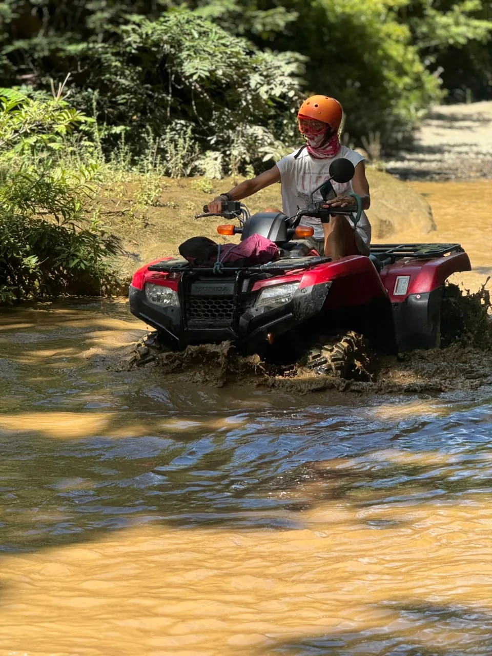ATV rider splashing through a shallow river crossing in the Guanacaste forest