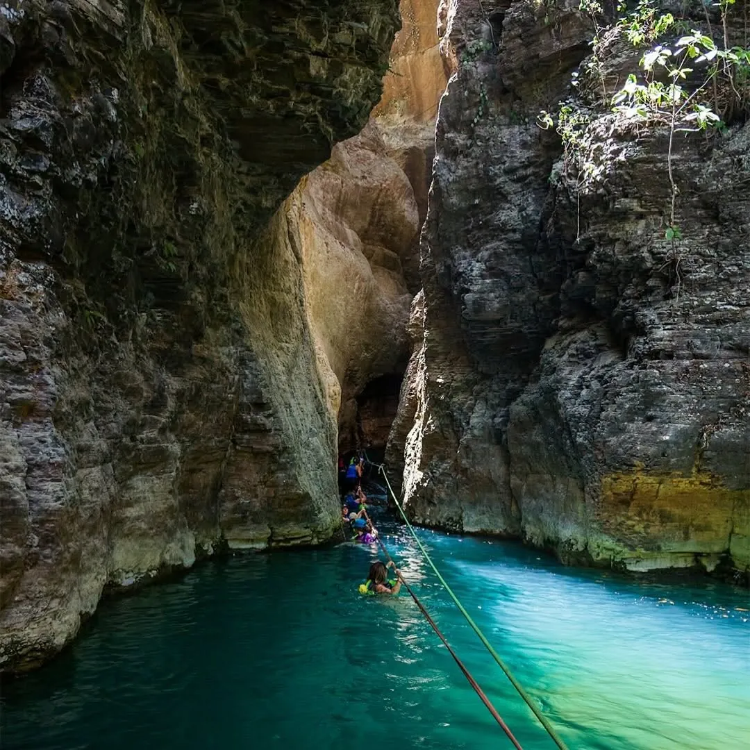 Guests in life jackets swimming through the turquoise La Leona canyon along a guide rope