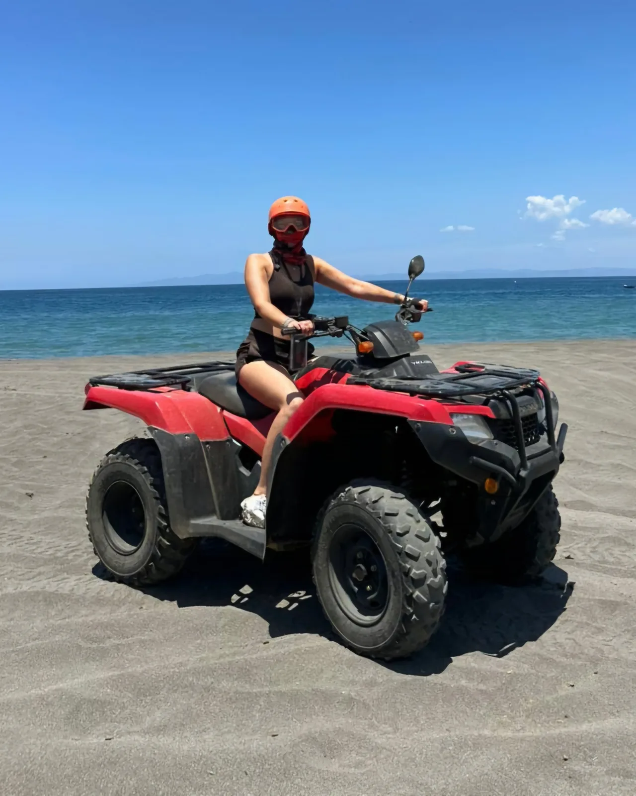 Rider on a red Honda ATV on the beach beside the Pacific near Playas del Coco