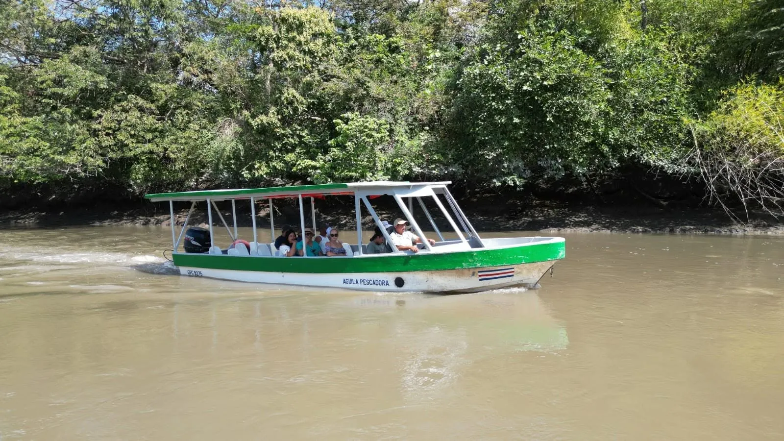 Guests on a covered boat cruising the Tempisque River on a Palo Verde wildlife tour