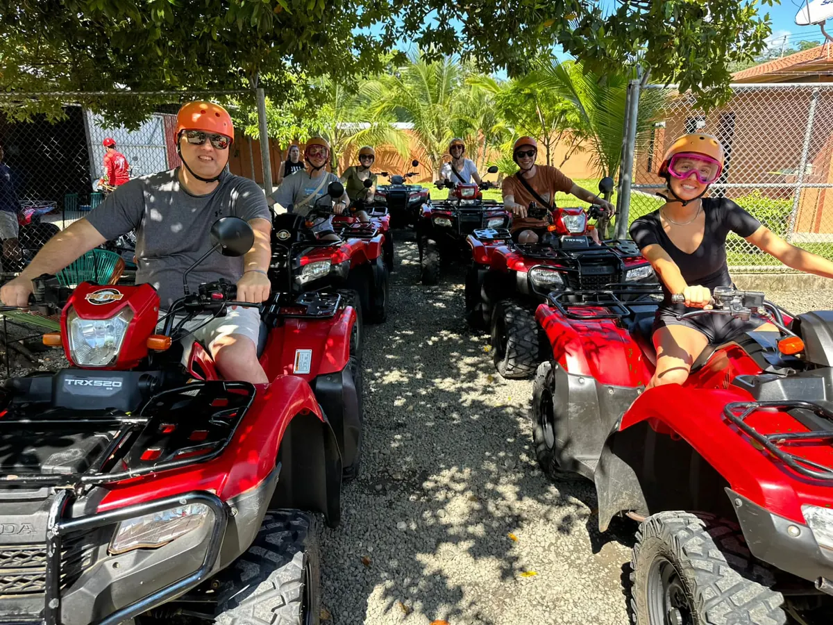 A group of riders in helmets and goggles lined up on red Honda ATVs, ready for a tour near Playas del Coco