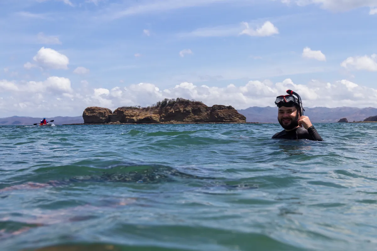 Smiling snorkeler in the Pacific off the Guanacaste coast, with a rocky islet behind