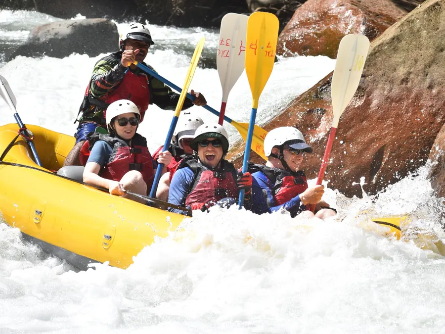 Rafters raising their paddles as their raft splashes through Tenorio River rapids in Guanacaste